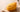 Golden crispy-coated food-shaped squishy with a curled strand coating and a small painted face, resting on a pale wooden table with soft warm daylight
