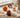 Four autumn-themed squishy toys — a fox, an acorn, a spiked hedgehog-shaped piece and an orange maple leaf — arranged together on a wooden desk in soft window light.